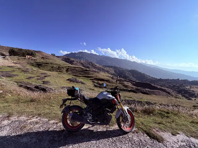 Moto parada na beira de uma estrada de terra, com morros ao fundo